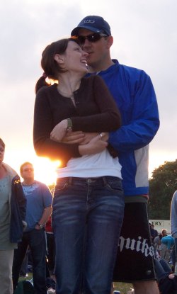 [A couple watching the concert, with the setting sun behind them]